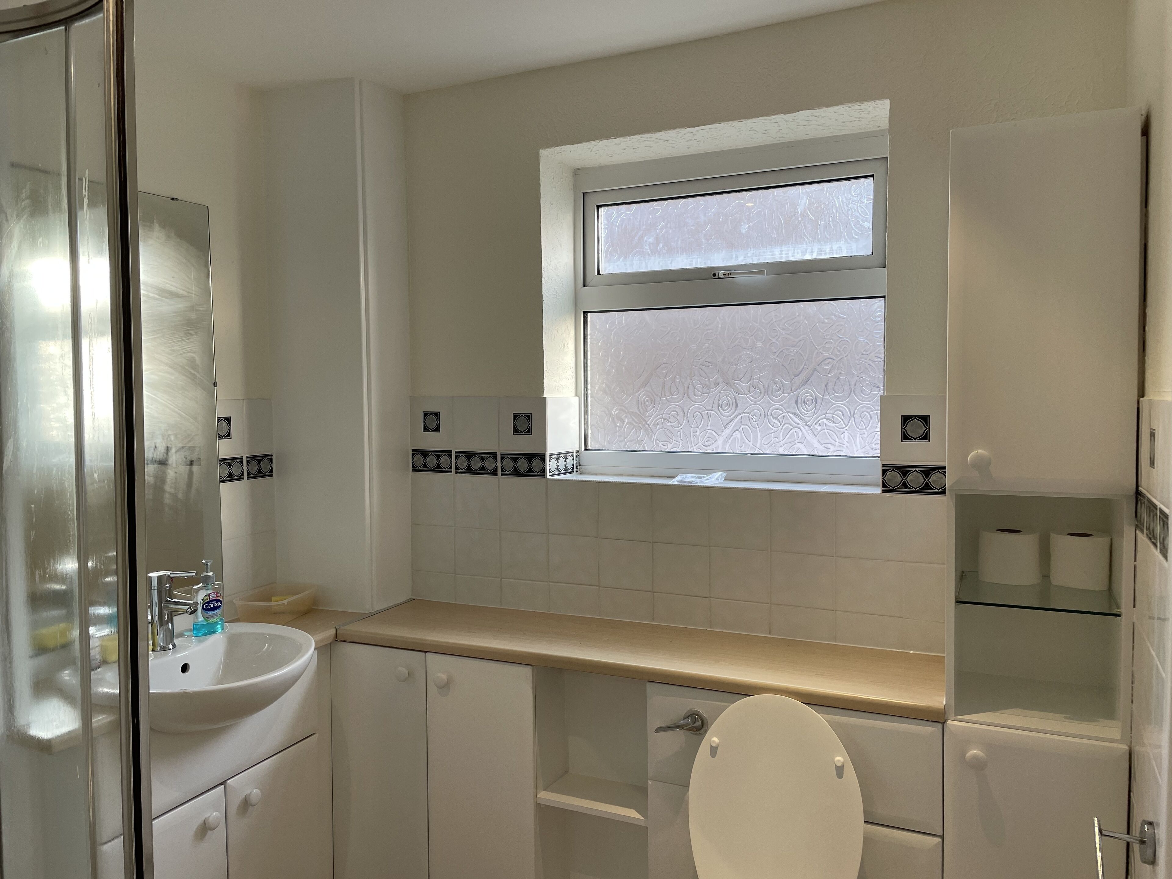 A bathroom with a white sink, a toilet, and a window above the sink.