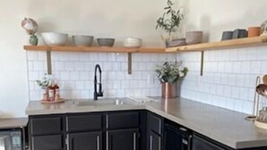 Una cocina con armarios oscuros, un salpicadero de azulejos blancos y una encimera de madera.