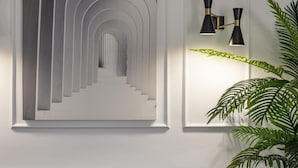 Um interior moderno com um sofá cinza estofado, uma grande obra de arte abstrata e uma luminária fixada na parede.