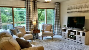 A cozy living room with a sofa, armchairs, a TV, and a wooden entertainment unit.