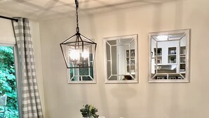 A dining area with a wooden table, white chairs, a bench, and a hanging light fixture.