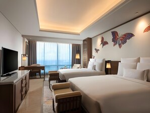 A hotel room with a TV, two beds, a desk, and a view of the city. - Hotel Tentrem Semarang (Semarang)