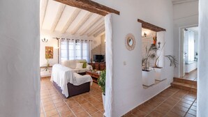 A cozy living room with a sofa, TV, and decorative plants. - Villa María del Carmen Frigiliana by Ruralidays (Málaga)