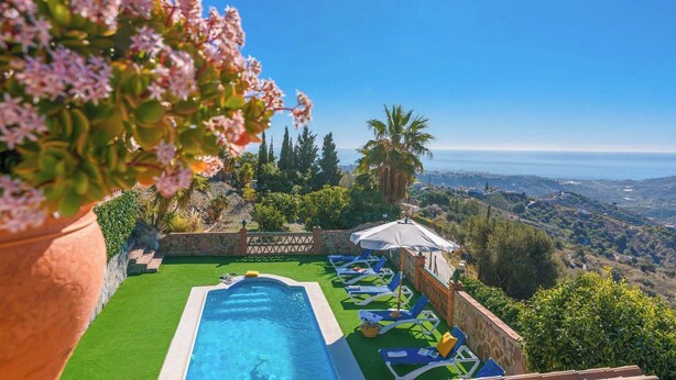 A swimming pool with a view of the ocean, surrounded by lounge chairs and a stone wall. - Villa María del Carmen Frigiliana by Ruralidays (Málaga)