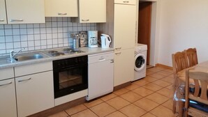 Une cuisine compacte équipée d’un lave-vaisselle, d’un four et d’un lave-linge.
