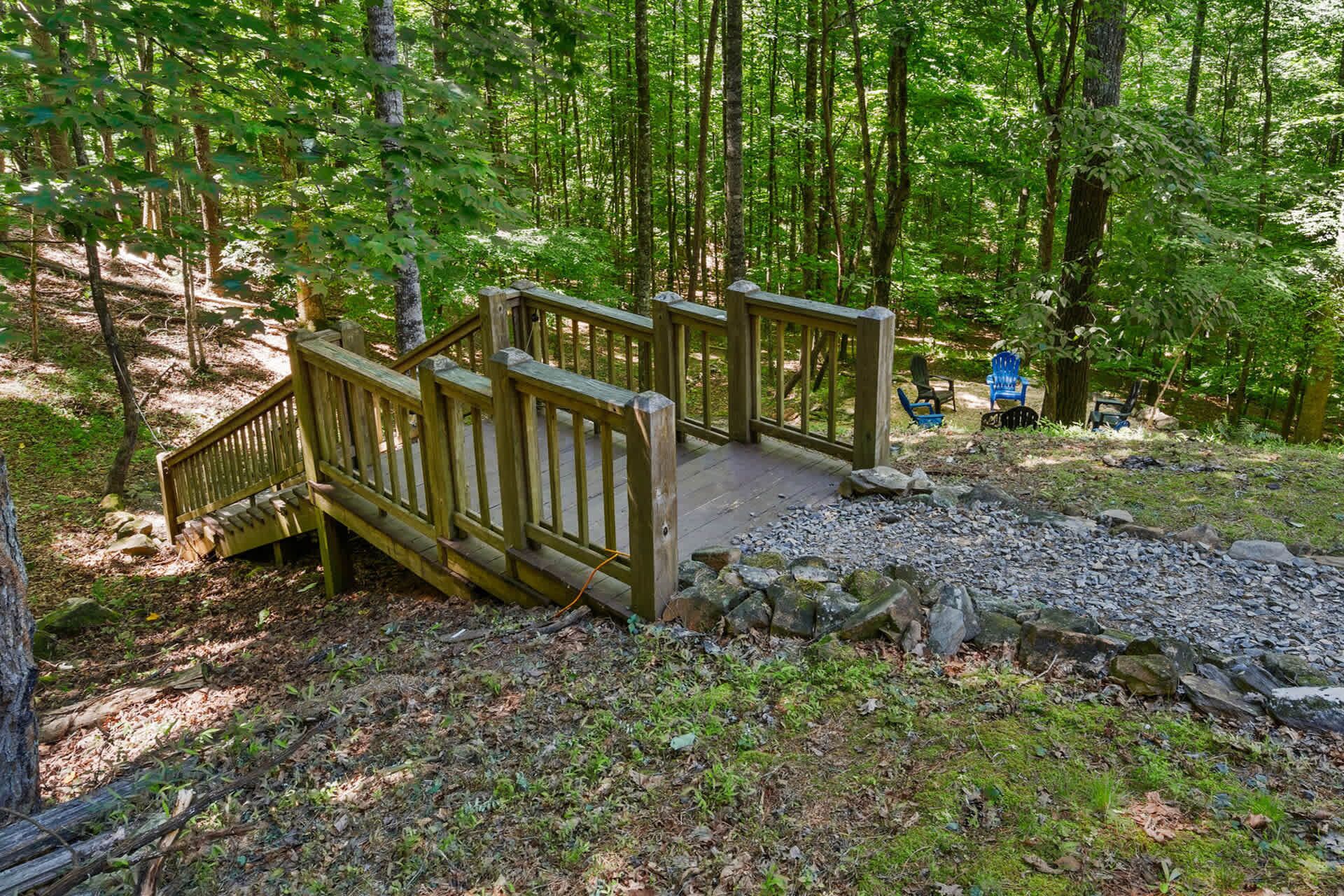 A wooden bridge in a forested area with a stone pathway and benches.