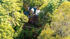 A large, two-story house surrounded by dense forest. - Hot Tub & Scenic Mountain Views, Game Room (Mineral Bluff)