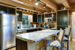 A kitchen with wooden cabinets, stainless steel appliances, and a central island with chairs.