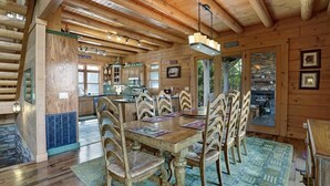 L'intérieur d'un chalet en bois comprend une table à manger, des chaises et un coin cuisine.