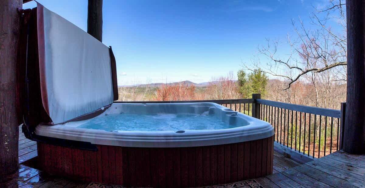 Una vasca idromassaggio su un pontile in legno con vista sulle montagne.