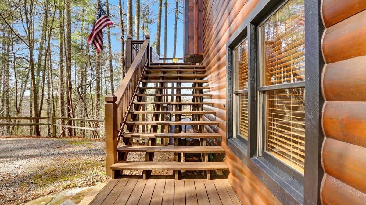 Eine Holztreppe führt zu einer Hütte mit Blick auf einen Wald.