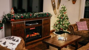 Un salon chaleureux avec une cheminée, un téléviseur et un sapin de Noël.