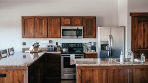 Une cuisine avec des armoires en bois, un four à micro-ondes, une cuisinière et un réfrigérateur.