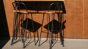 Un coin bar avec deux chaises et une vue sur les montagnes et les arbres.