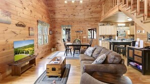 Un intérieur de chalet chaleureux, avec un revêtement en bois, un coin repas et une cuisine.