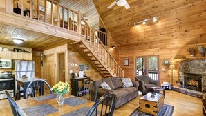 Une cabine spacieuse avec un intérieur en bois, un coin repas, un salon doté d’une cheminée et un escalier menant à un niveau supérieur.