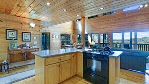 A spacious kitchen with wooden cabinetry, a central island, and a large stove. - Romantic Cabin w/ Hot Tub & Grand Fire Pit (Mineral Bluff)