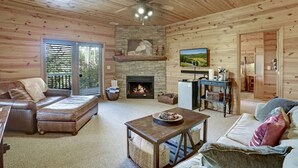 A cozy log cabin interior with a fireplace, a television, and a comfortable seating area. - Romantic Cabin w/ Hot Tub & Grand Fire Pit (Mineral Bluff)