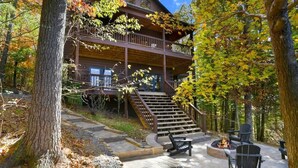 A two-story log cabin with a fire pit and outdoor seating area. - Romantic Cabin w/ Hot Tub & Grand Fire Pit (Mineral Bluff)