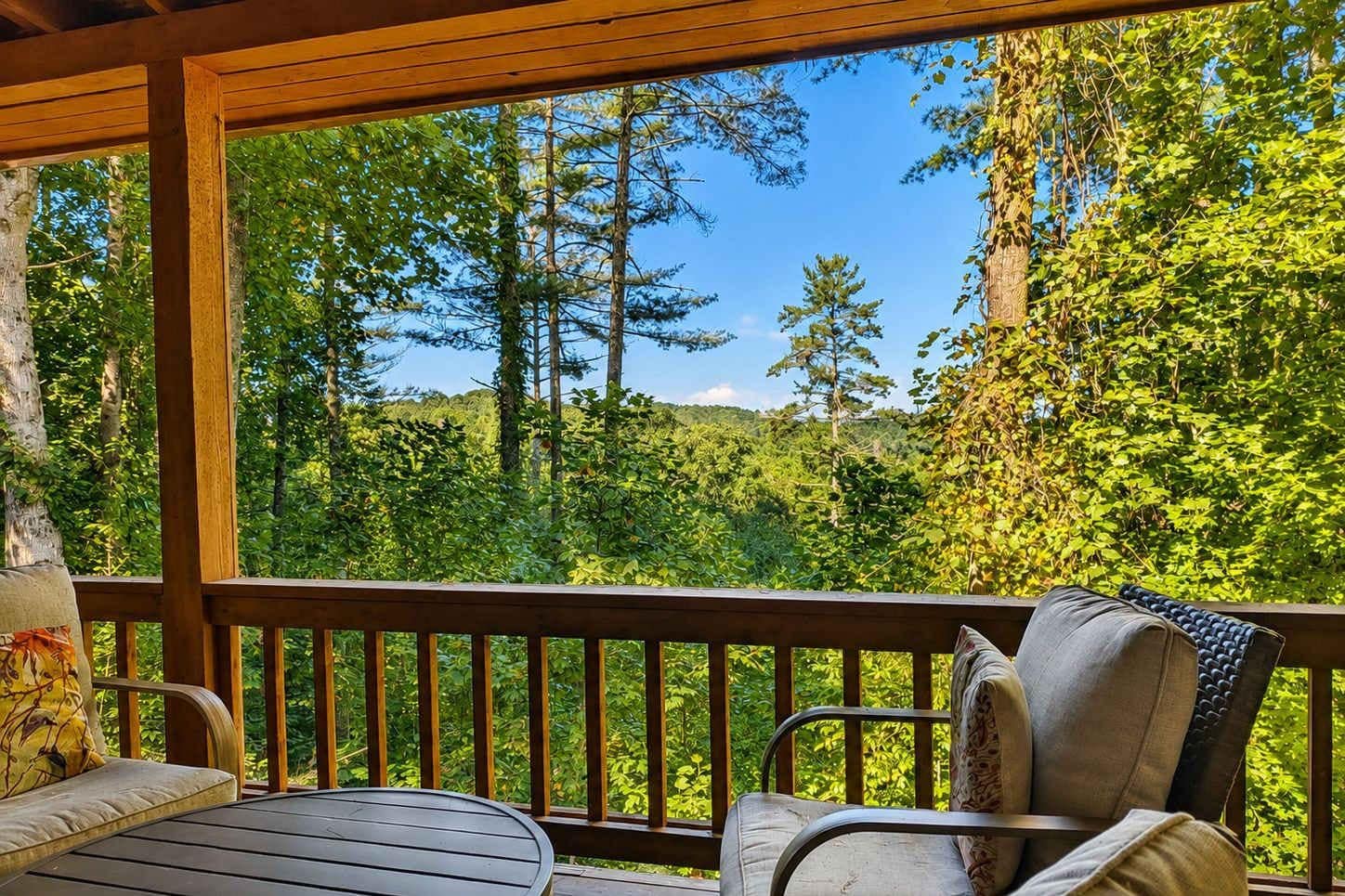 Eine Terrasse im Freien mit Holzgeländern, einem Tisch und zwei Stühlen.