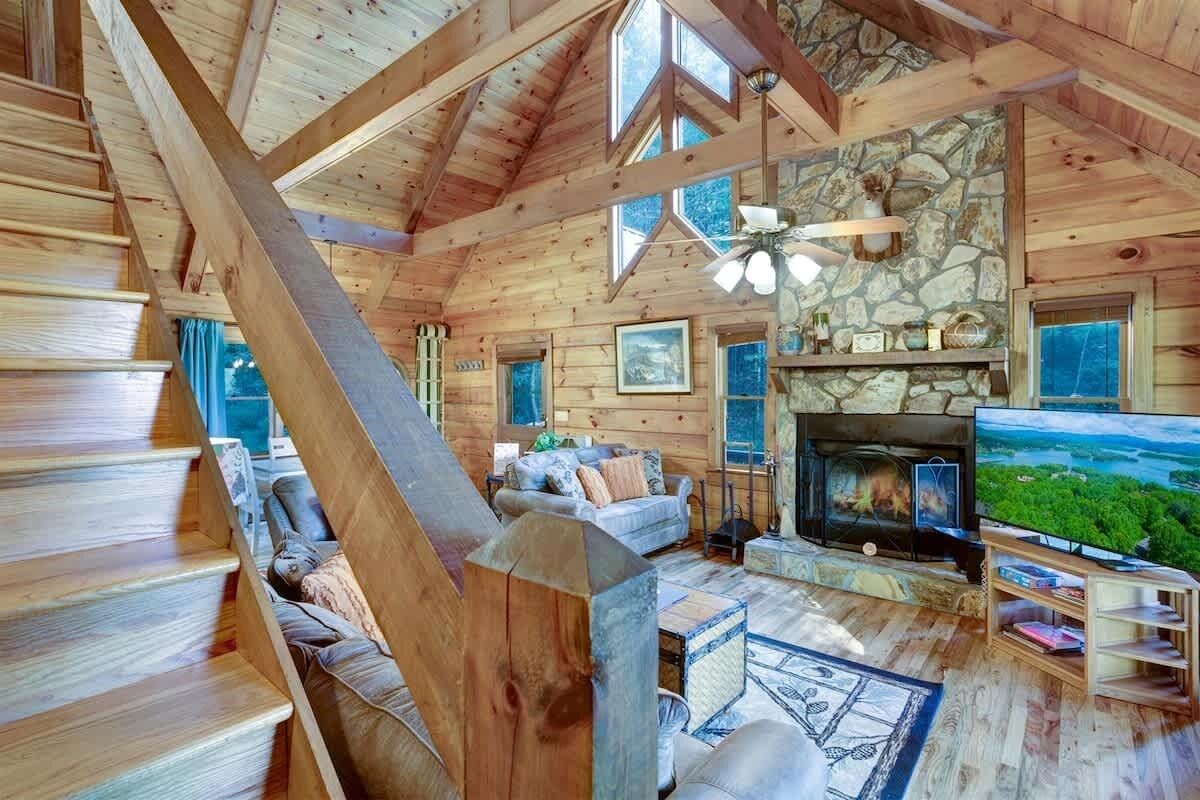 A wooden cabin interior with a fireplace, a television, and a stone wall.