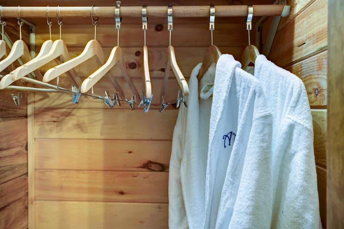 A wooden cabin interior with a wooden rack holding white towels and wooden hangers.