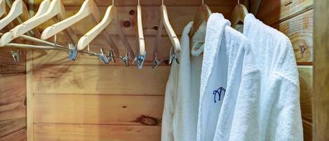 A wooden cabin interior with a wooden rack holding white towels and wooden hangers.