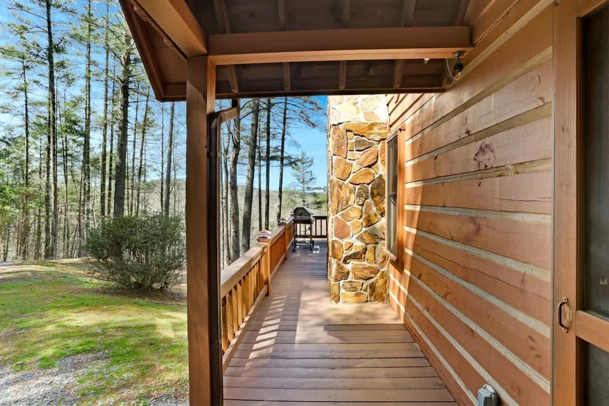 A wooden deck leading to a stone wall, surrounded by a forest.