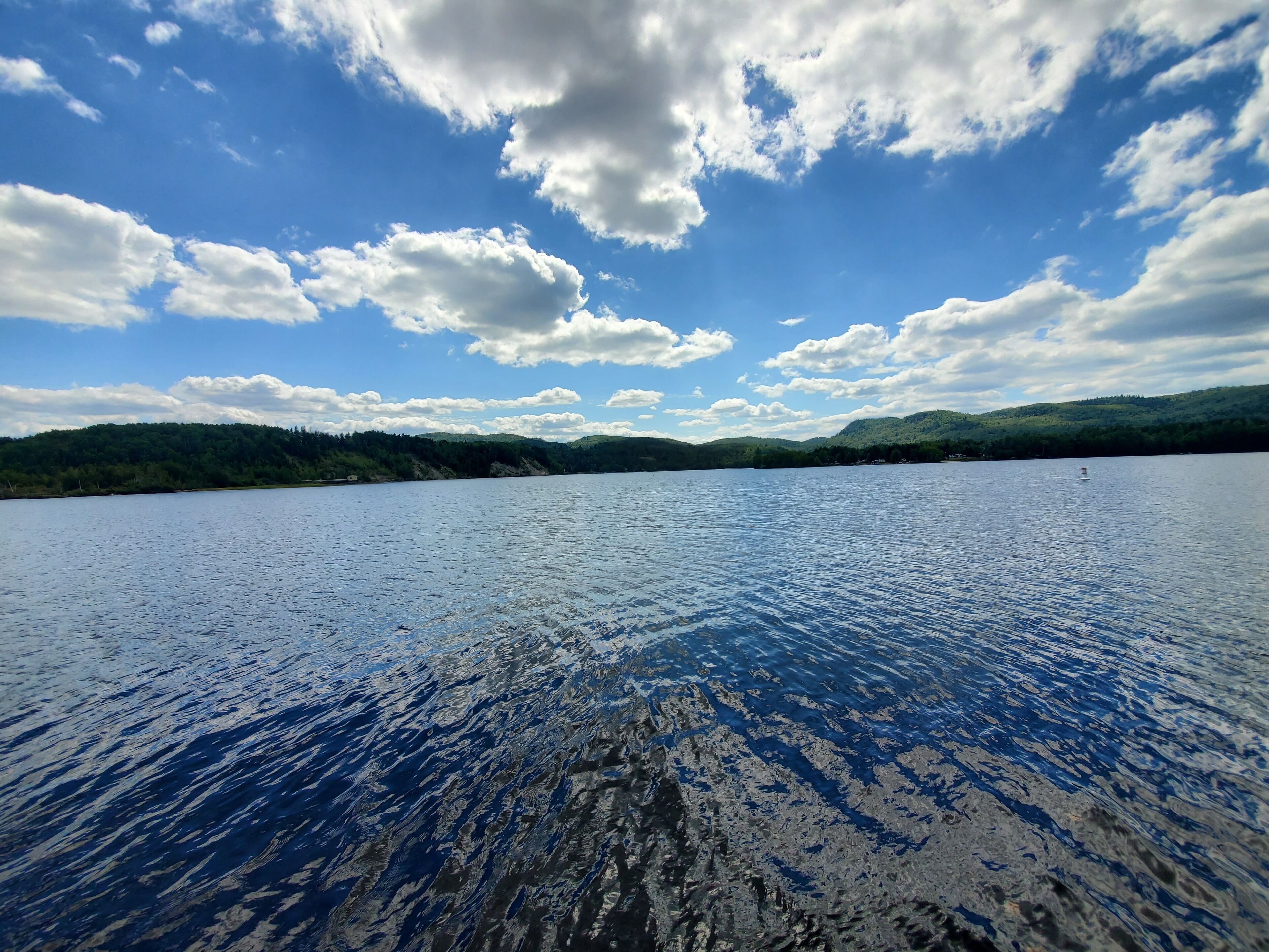 Um lago calmo com céu limpo e colinas ao longe.