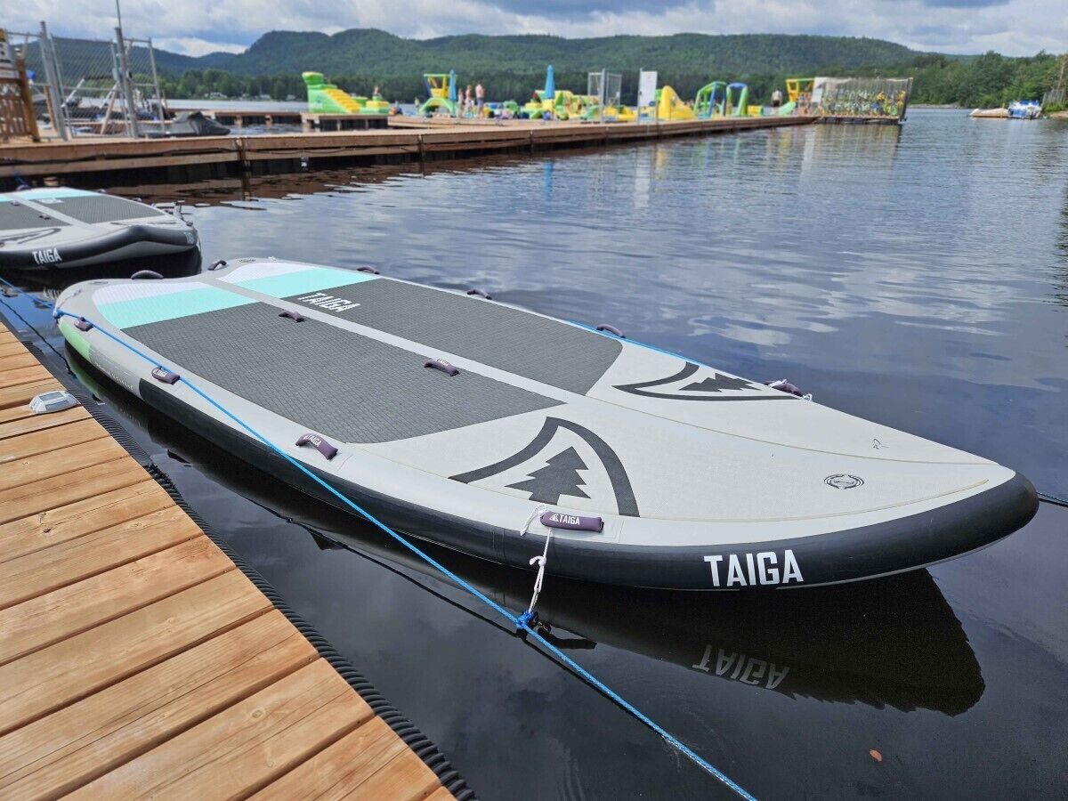 Une planche de paddle avec la marque « TAIGA » sur un quai en bois.