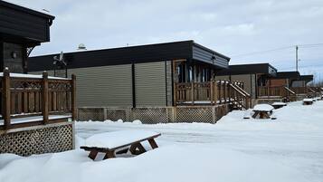 Una hilera de cabañas con terrazas de madera y suelo cubierto de nieve.