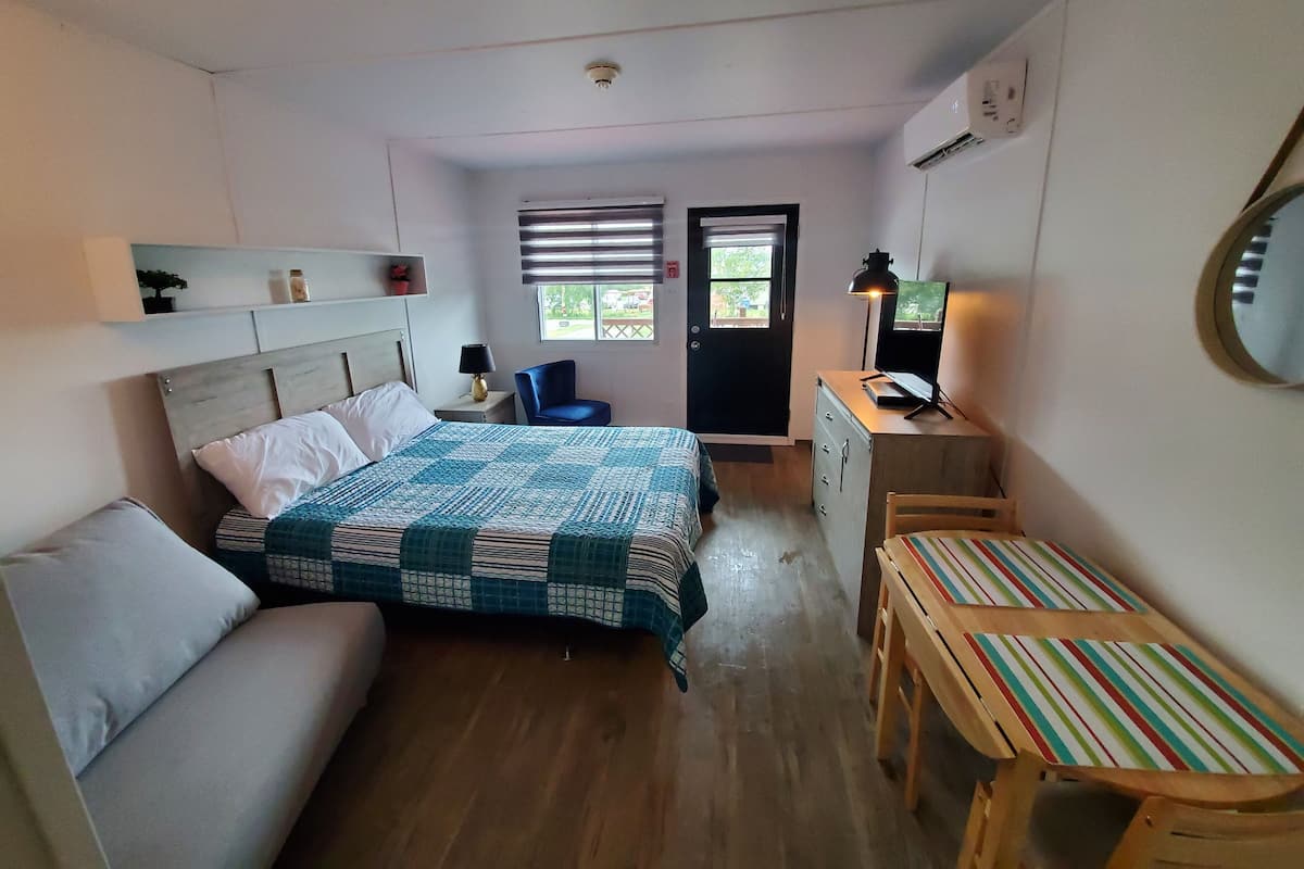 Ein kleines Zimmer mit Bett, Schreibtisch, Stuhl und einem kleinen Tisch.