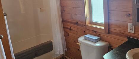 A wooden cabin bathroom with a shower, toilet, and sink.