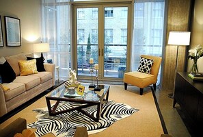 Relax in this stylish living room with a beige sofa, patterned cushions, and a glass coffee table.