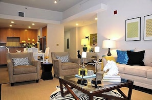 Relax in this stylish living room with a sofa, coffee table, and rug, plus a kitchen with wooden cabinets and refrigerator.