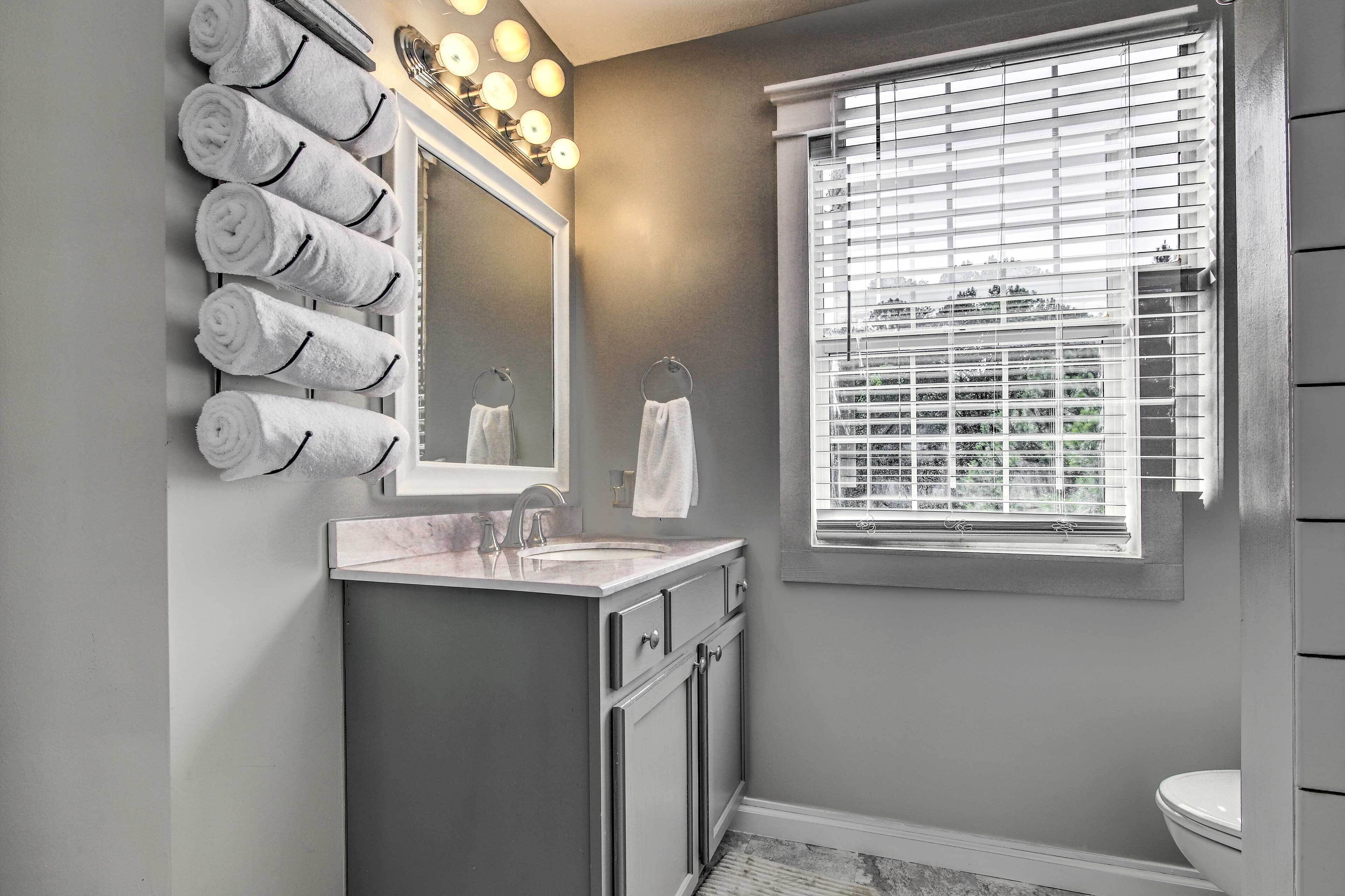 A bathroom with a vanity, a mirror, and a window with blinds.