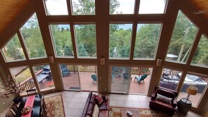 Ein großzügiger Wohnraum mit einer großen Schiebeglasdoor, die auf eine Terrassenfläche im Freien führt. Innen befindet sich eine Essecke mit Tisch und Stühlen, ein Sofa und ein Couchtisch.