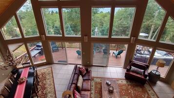 A spacious living room with a large sliding glass door leading to an outdoor deck. Inside, there is a dining area with a table and chairs, a sofa, and a coffee table.