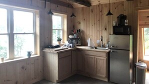 A kitchen with wooden cabinets, a stainless steel refrigerator, a microwave, and a sink. - Lovelyt one bedroom nestled in the white mountains and the lakes region of NH (ORFORD)