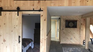 A wooden interior with a bed, a dartboard, and a sofa. - Lovelyt one bedroom nestled in the white mountains and the lakes region of NH (ORFORD)