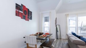 Un comedor con una mesa de madera, sillas y un banco. Hay un sofá con un cojín y un espejo apoyado en la pared.