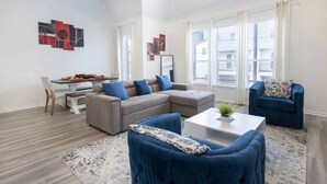 Una sala de estar moderna con un sofá modular, un sillón azul y una zona de comedor con una mesa dispuesta para dos personas.