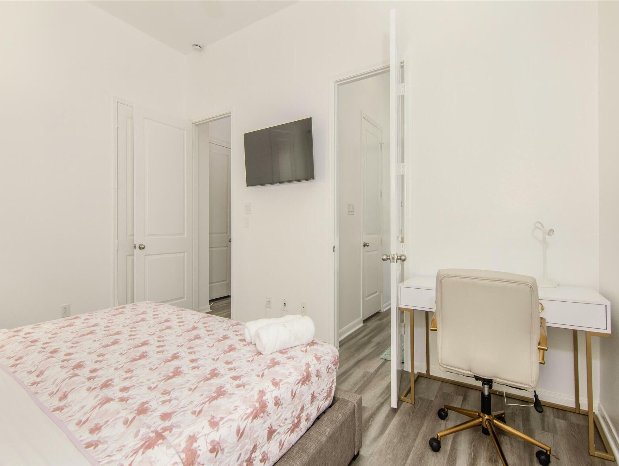 Una habitación de hotel con una cama, un escritorio, una silla y un televisor.