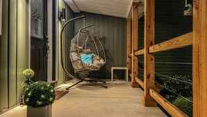 Un espace intérieur accueillant, avec un fauteuil suspendu, une petite table et une plante en pot.