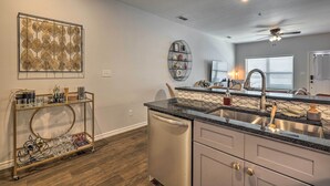A modern kitchen with a dishwasher, stainless steel sink, and a two-tiered metal cart. - Single-Story Condo < 1 Mile From Downtown! (Fredericksburg)