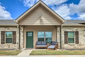 A house with a stone facade, a green door, and a porch with two chairs and a table.