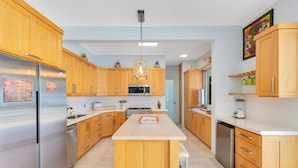 Een moderne keuken met houten kastjes, roestvrijstalen apparatuur en een centraal eiland.