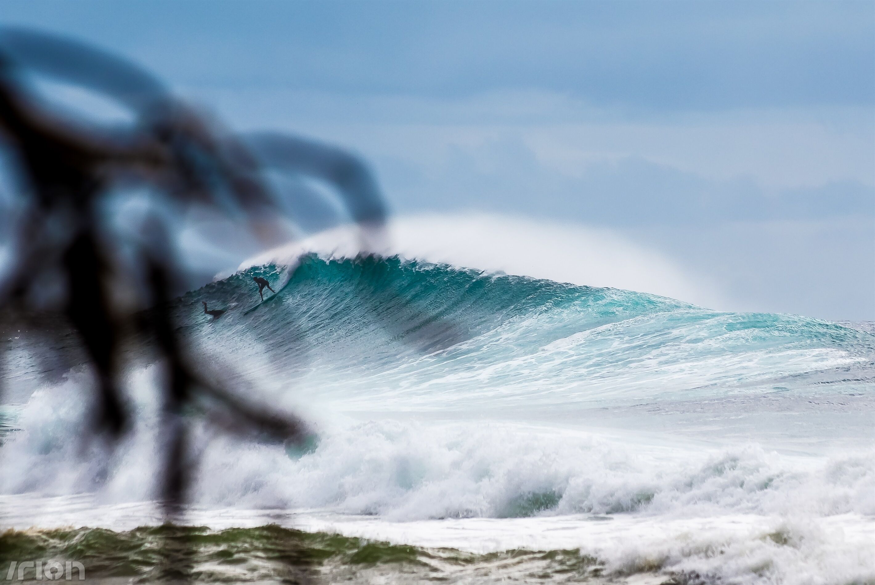 A large wave in the ocean with a surfer riding it.