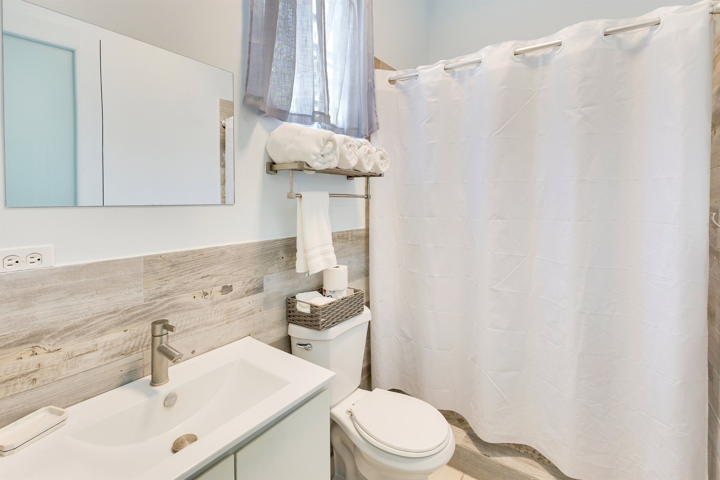 A modern bathroom with a sink, toilet, and shower curtain.