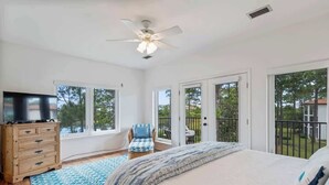 A bedroom with a bed, a television on a wooden dresser, a chair, and large windows with a view of the outdoors. - Fall in Love with Florida!-Now at Reduced Rates (Santa Rosa Beach)